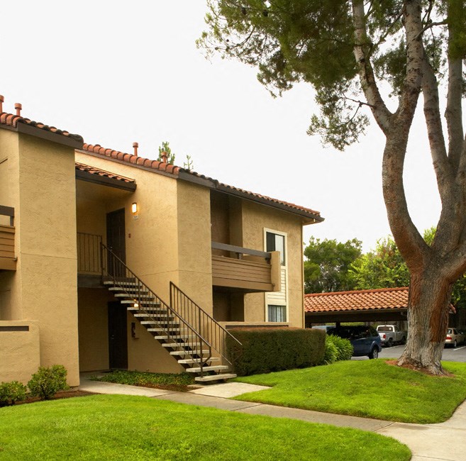 an apartment building with stairs and a tree