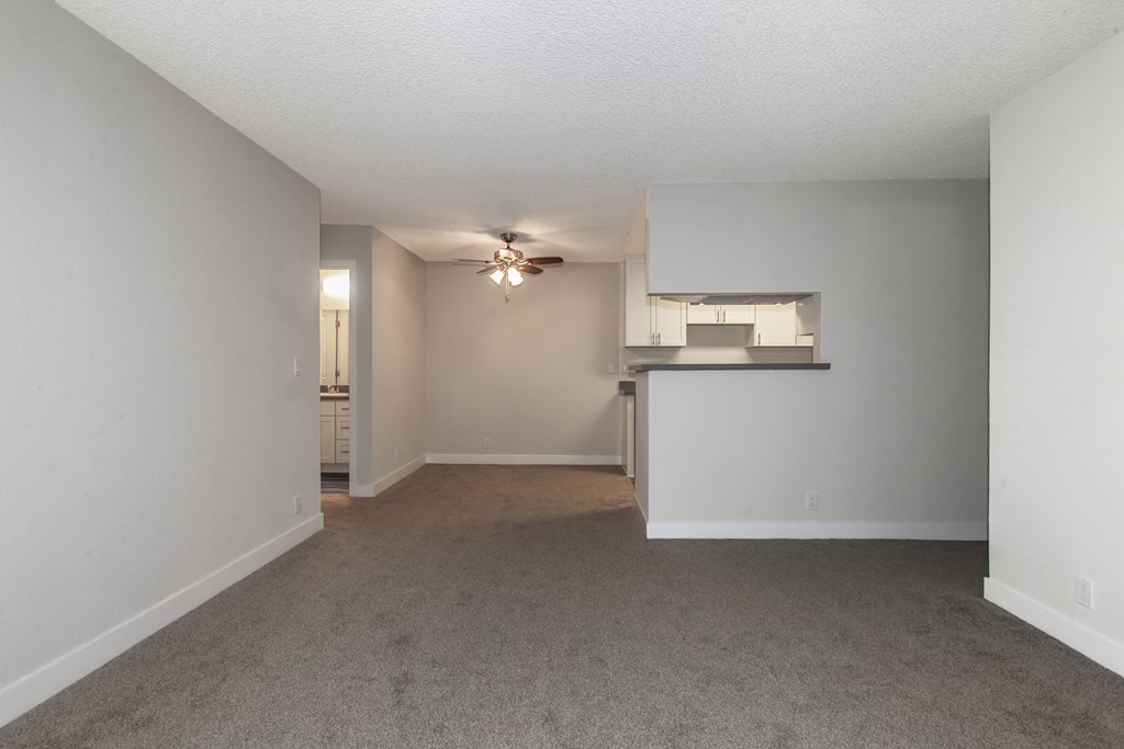 an empty living room and kitchen with a ceiling fan