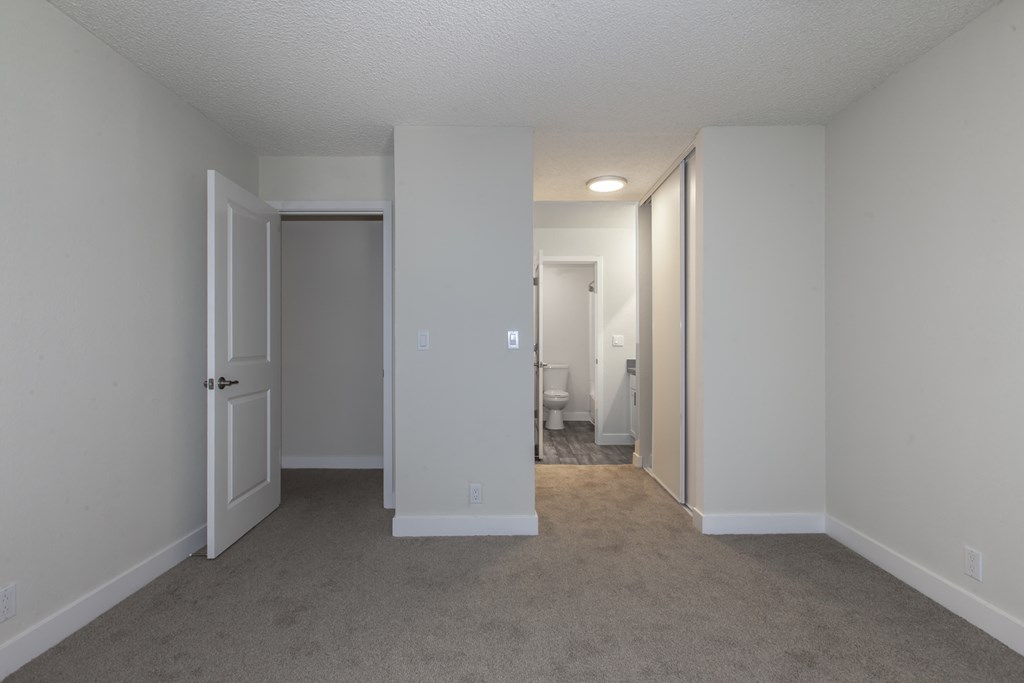 an empty living room with white walls and a door to a bathroom