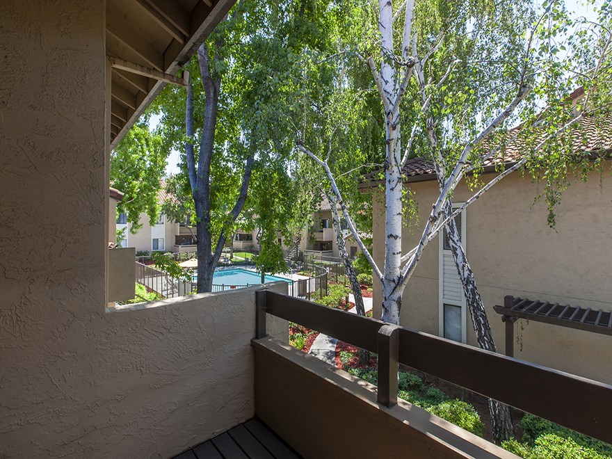 a balcony with a view of a pool and trees