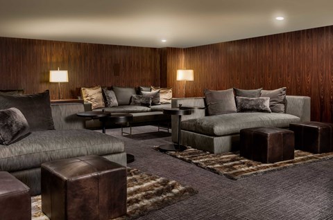 A living room with a grey couch and a brown ottoman.