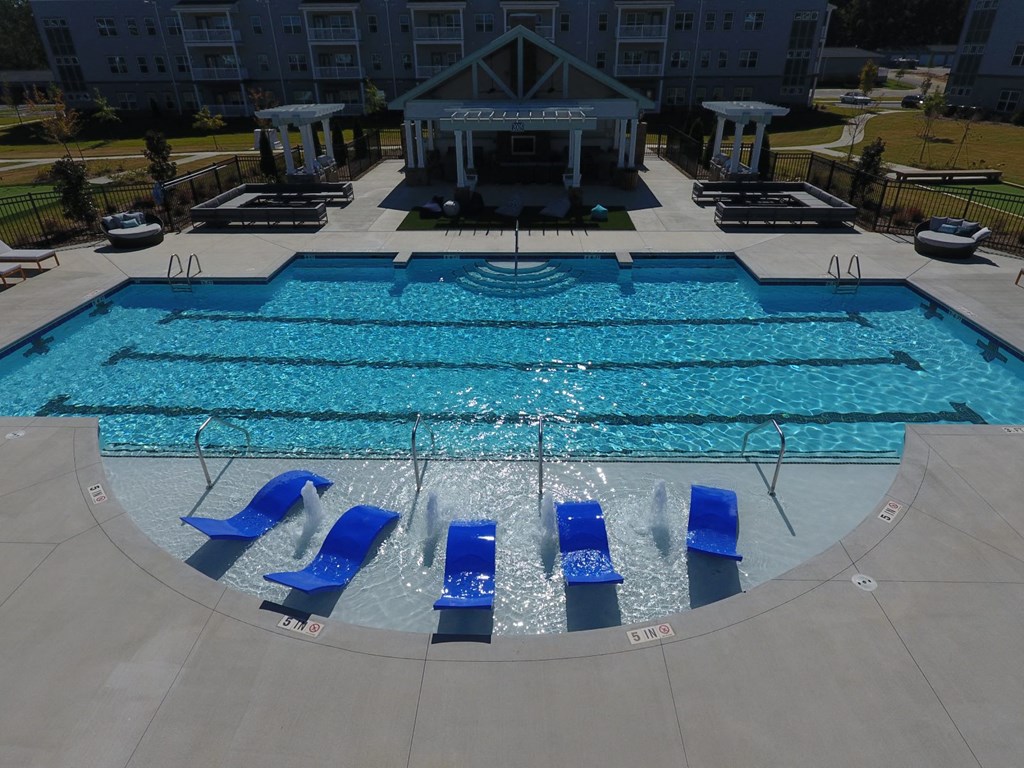 a swimming pool with blue lounge chairs in front of a hotel pool