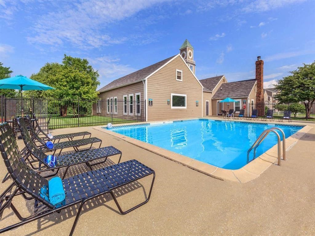 a pool with chairs and a house in the background