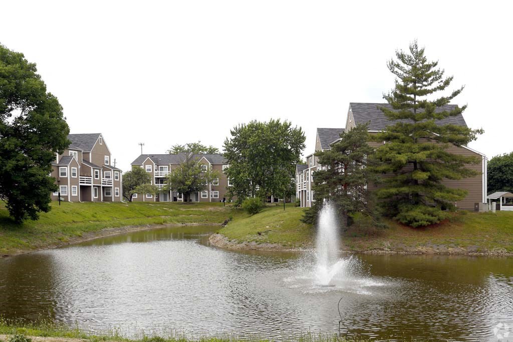 a fountain in a pond with houses in the background