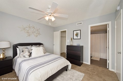 A bedroom with a large bed and a ceiling fan.