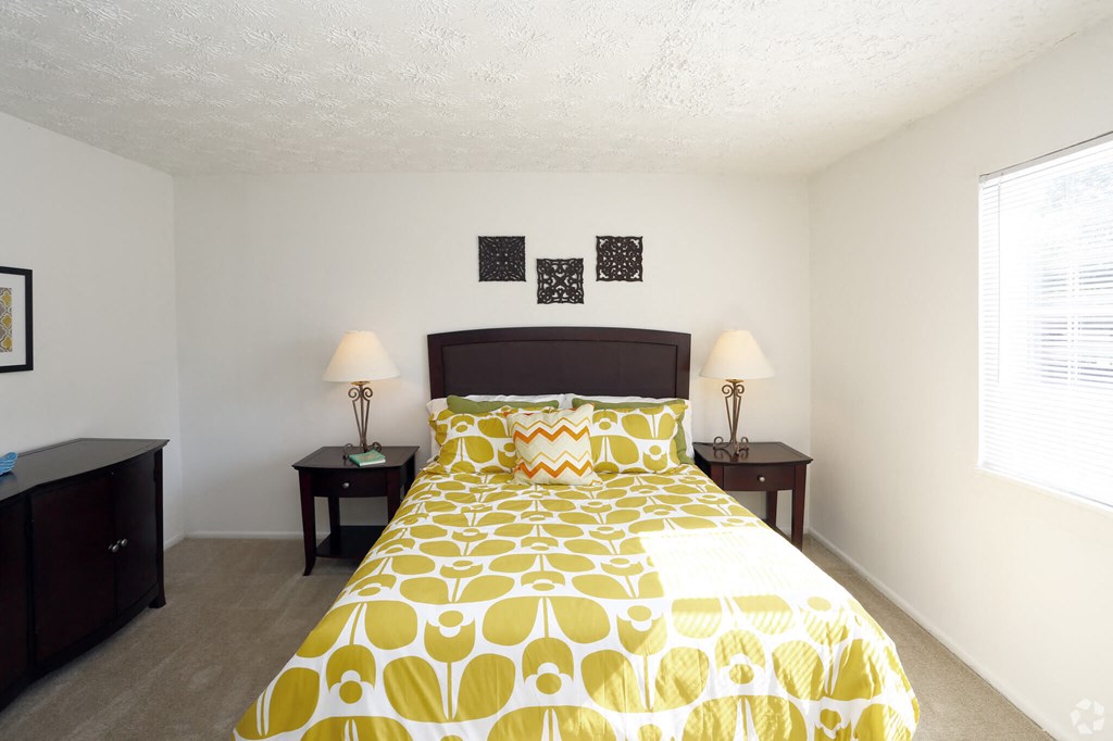 a bedroom with a yellow and white bed and a window