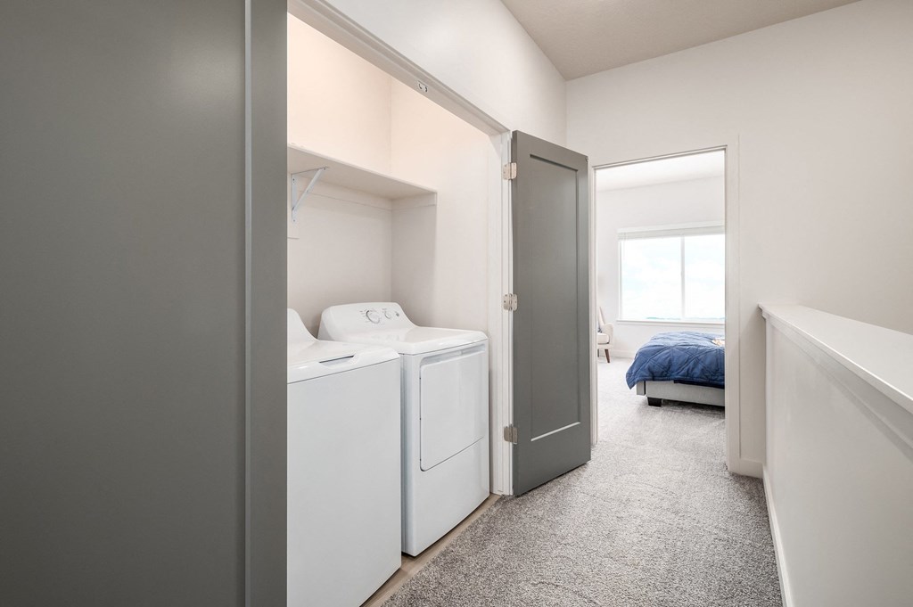 a laundry room with washer and dryer and a bedroom with a bed