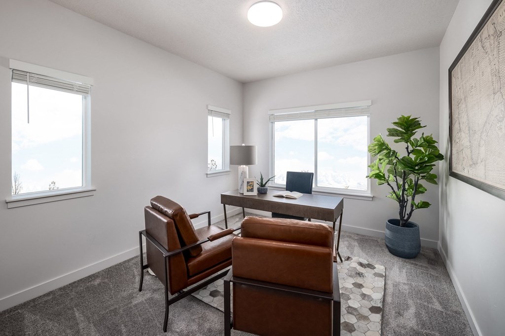 a living room with two leather chairs and a desk with a plant