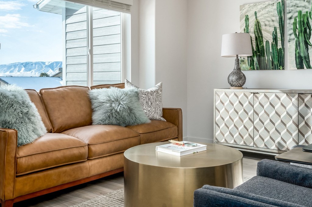 a living room with a brown couch and a table    and a window