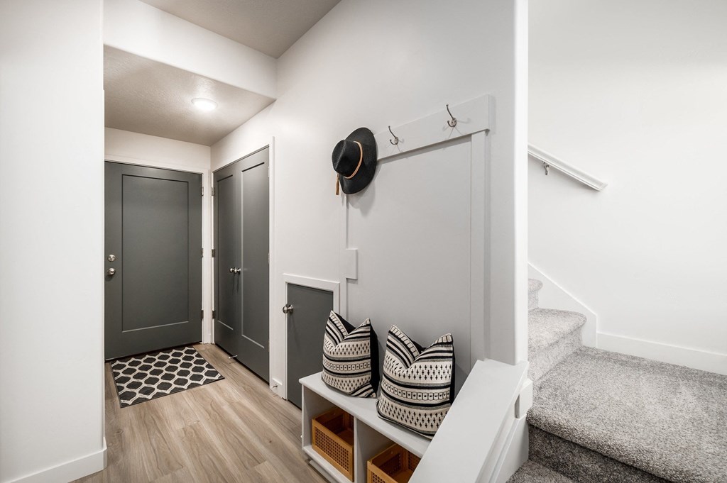 a entryway with a staircase and a black hat on the wall and a hallway