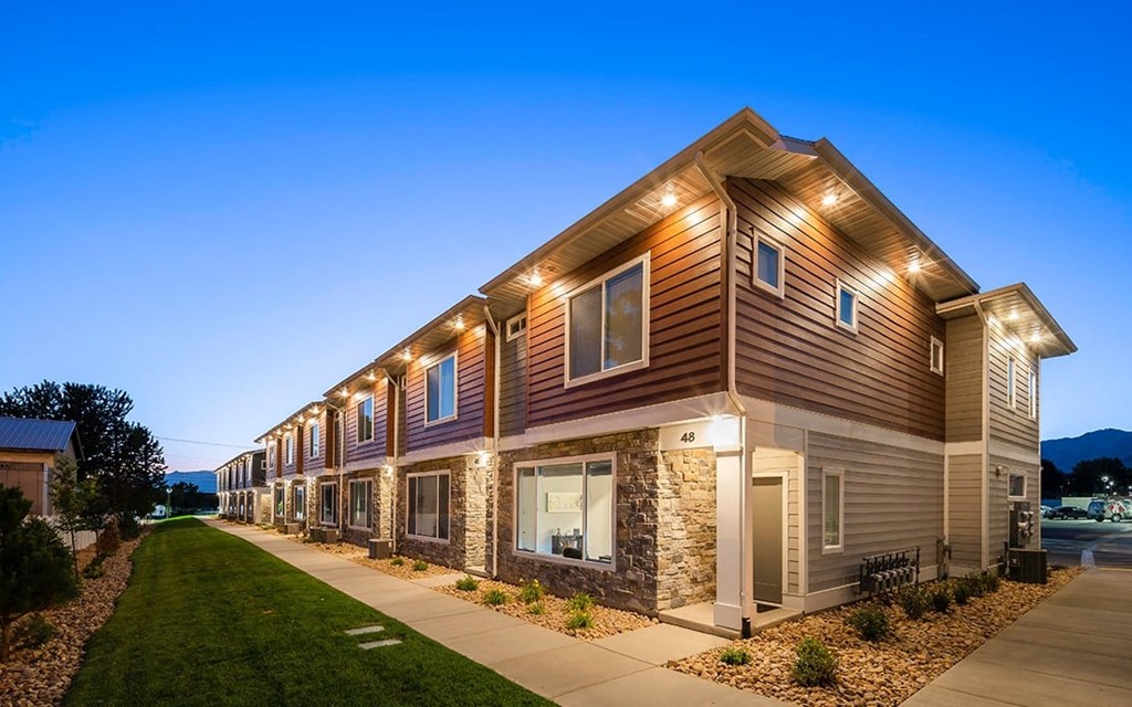 a row of houses with lights on and a sidewalk