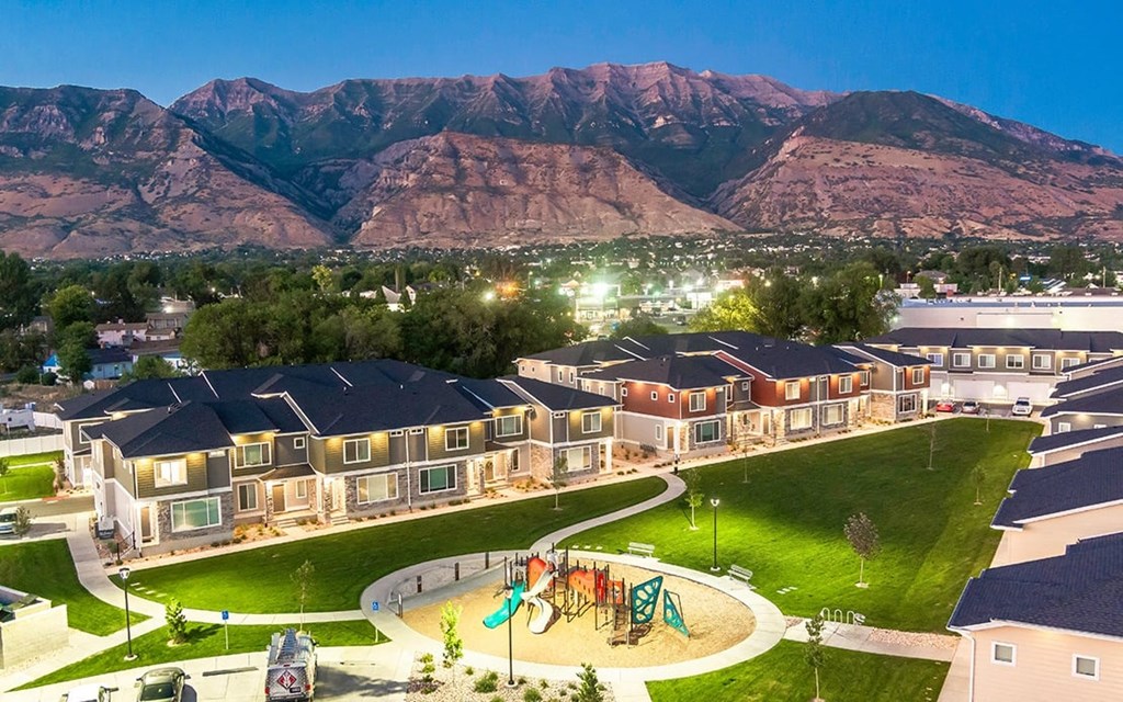 an aerial view of homes with a playground and mountains in the background