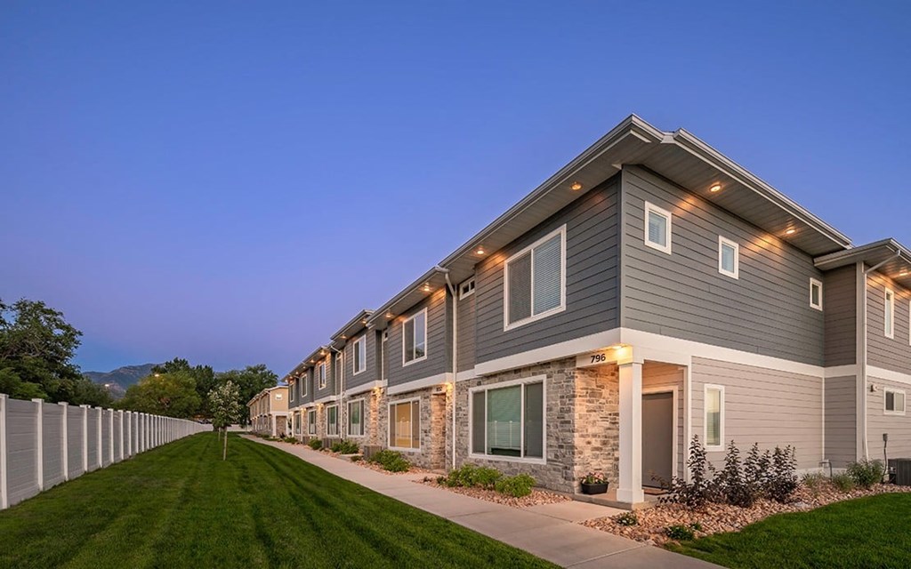 a row of town homes with grass and a sidewalk