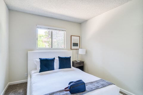 A bedroom with a white bed and a window.