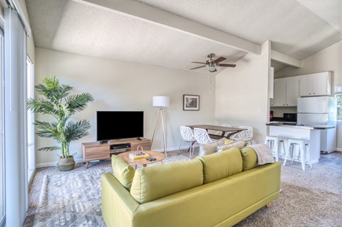 A living room with a yellow couch and a television.
