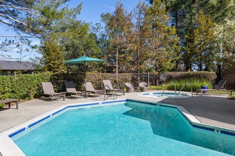 a swimming pool with chairs and a poolside umbrella