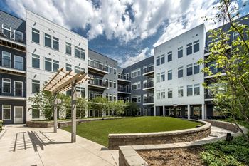 an outdoor courtyard with grass and trees in the middle of modern buildings