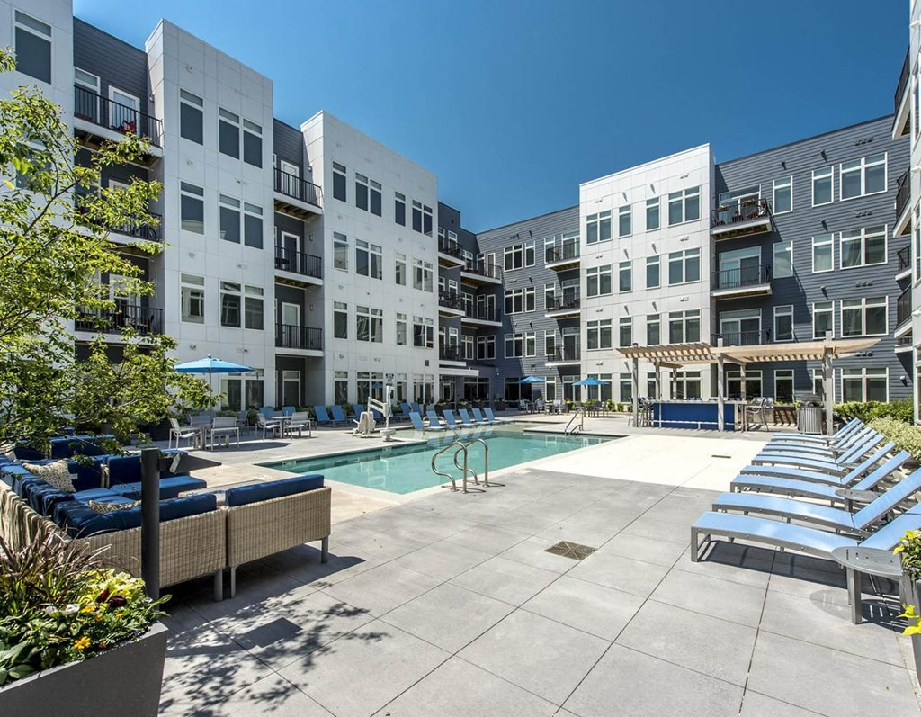 an apartment building with a pool and lounge chairs