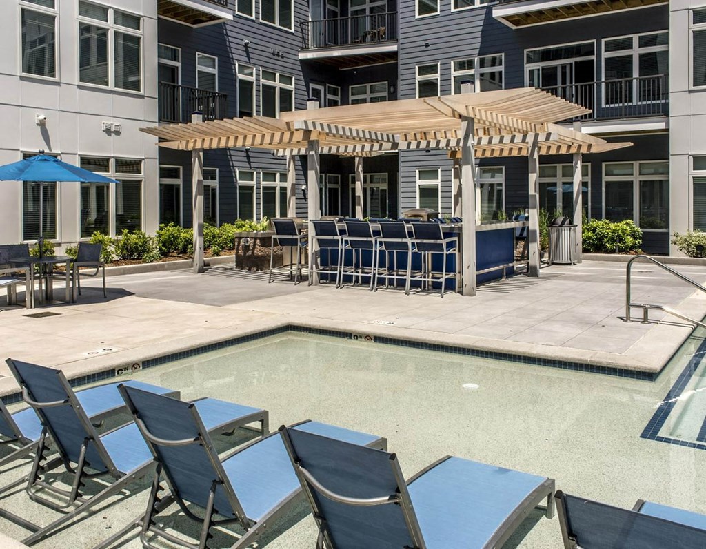 a pool with chairs and umbrellas next to a building