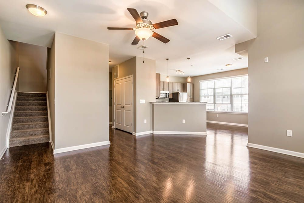 an empty living room and kitchen with a ceiling fan