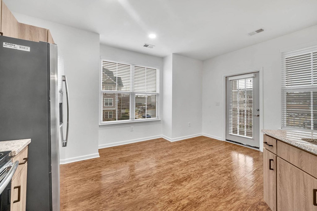 an empty kitchen and living room with a refrigerator and a window