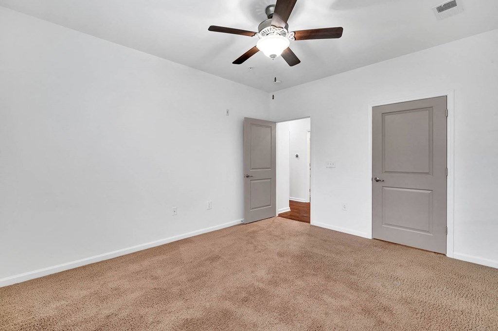 an empty living room with a ceiling fan and a door