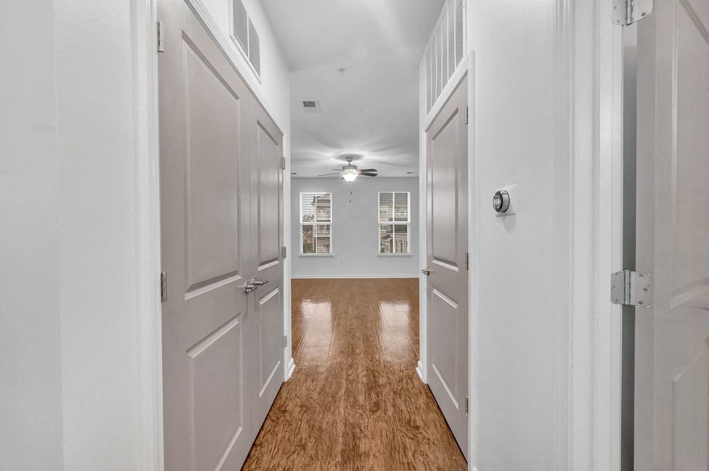 a long hallway with white doors and a ceiling fan