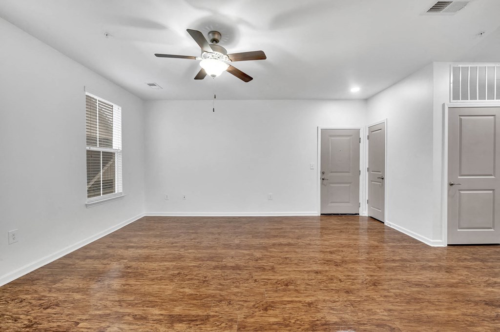 an empty living room with a ceiling fan and a closet