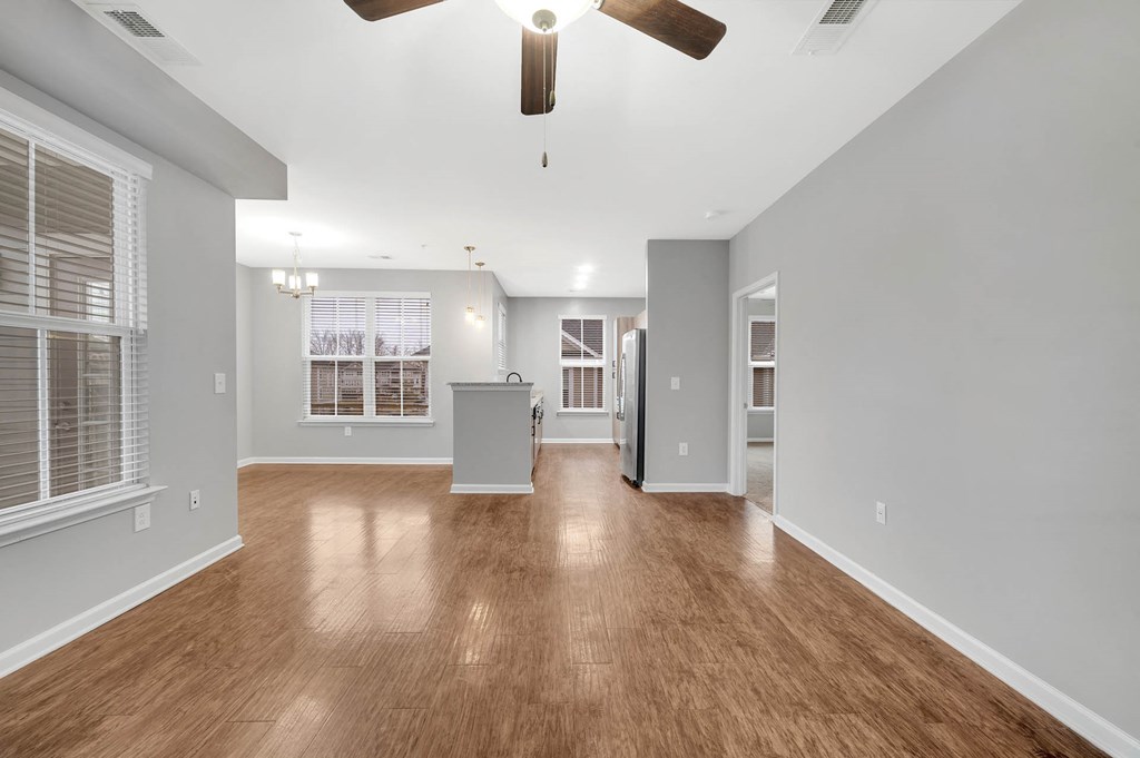 an empty living room with wood floors and a ceiling fan
