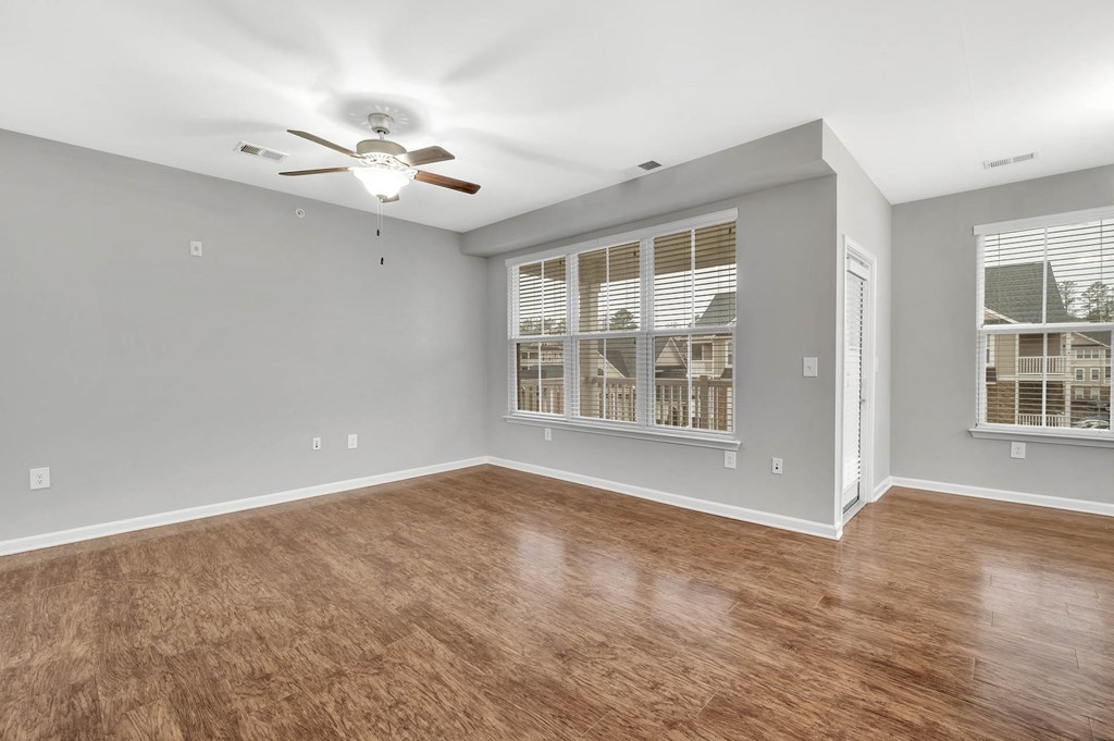 an empty living room with a ceiling fan and a window