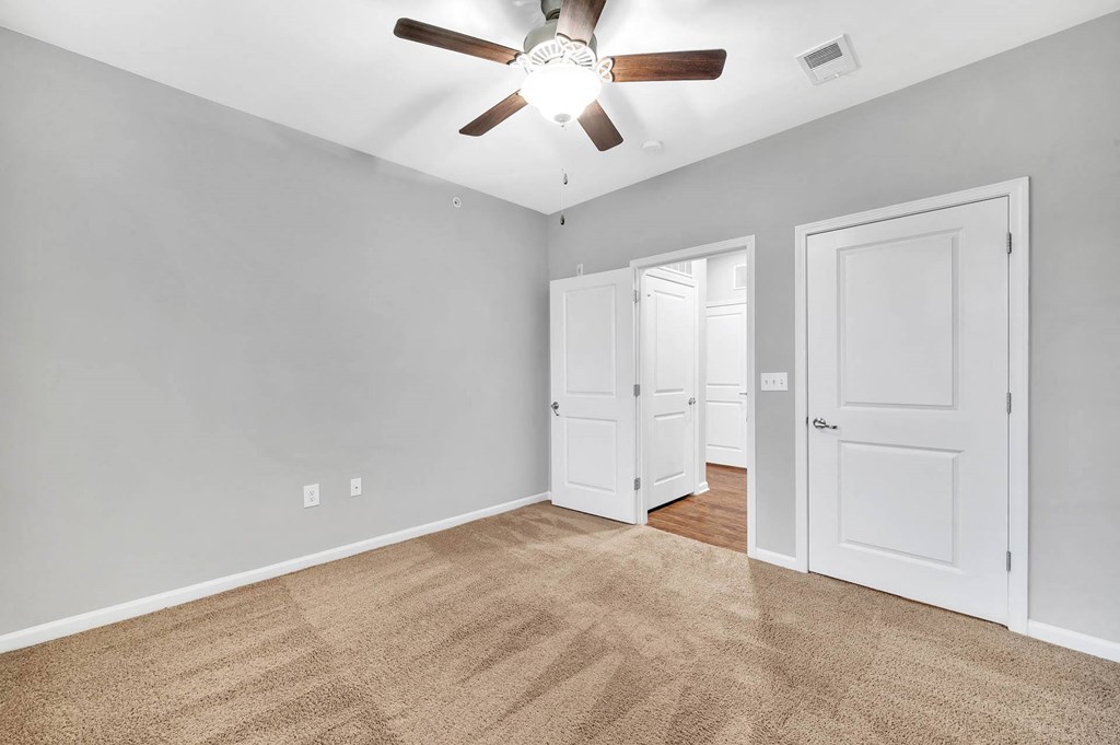 a bedroom with two doors and a ceiling fan