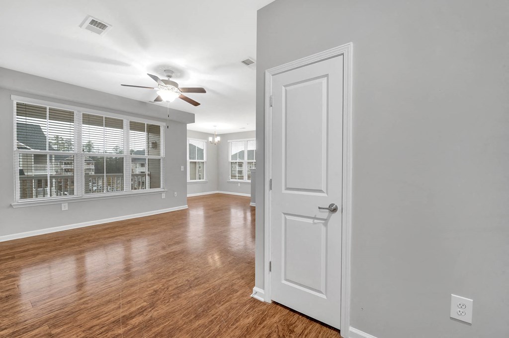 an empty living room with a white door and a ceiling fan