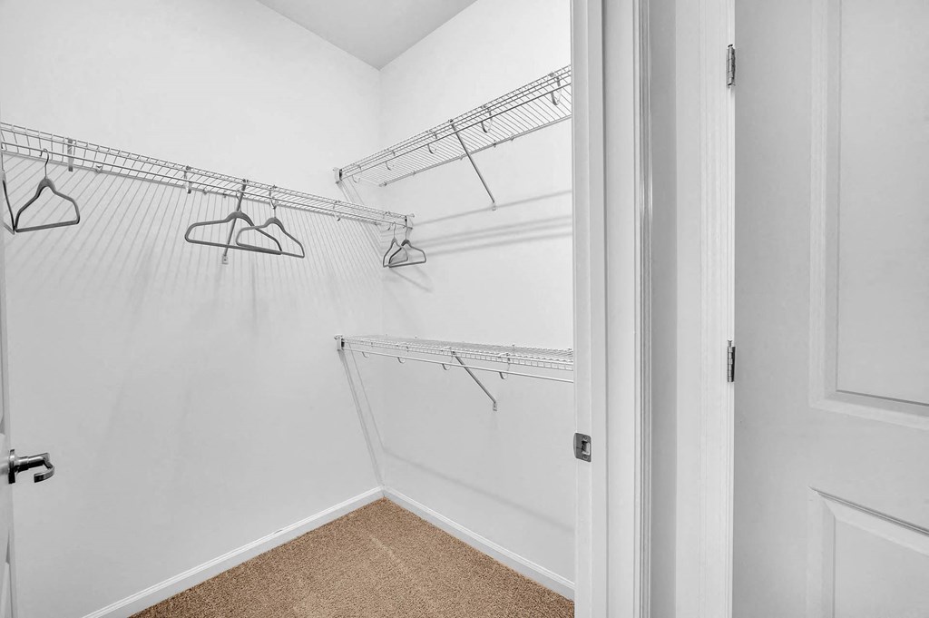 a closet in a bedroom with white walls and hanging racks