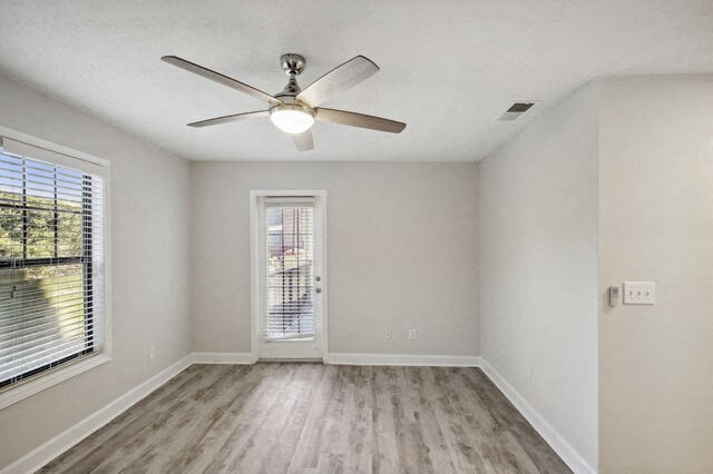 an empty living room with a ceiling fan and a window