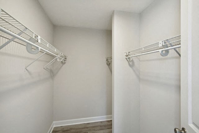 a walk in closet with white walls and a mirrored closet door
