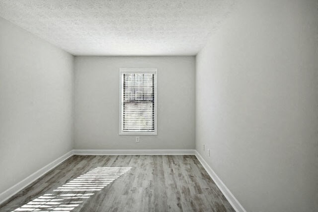 an empty room with a window and wood floors