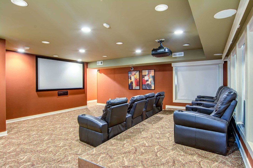 a theater room with leather chairs and a tv