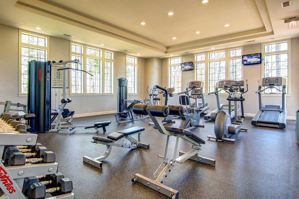 a gym with weights and cardio equipment on the floor and windows