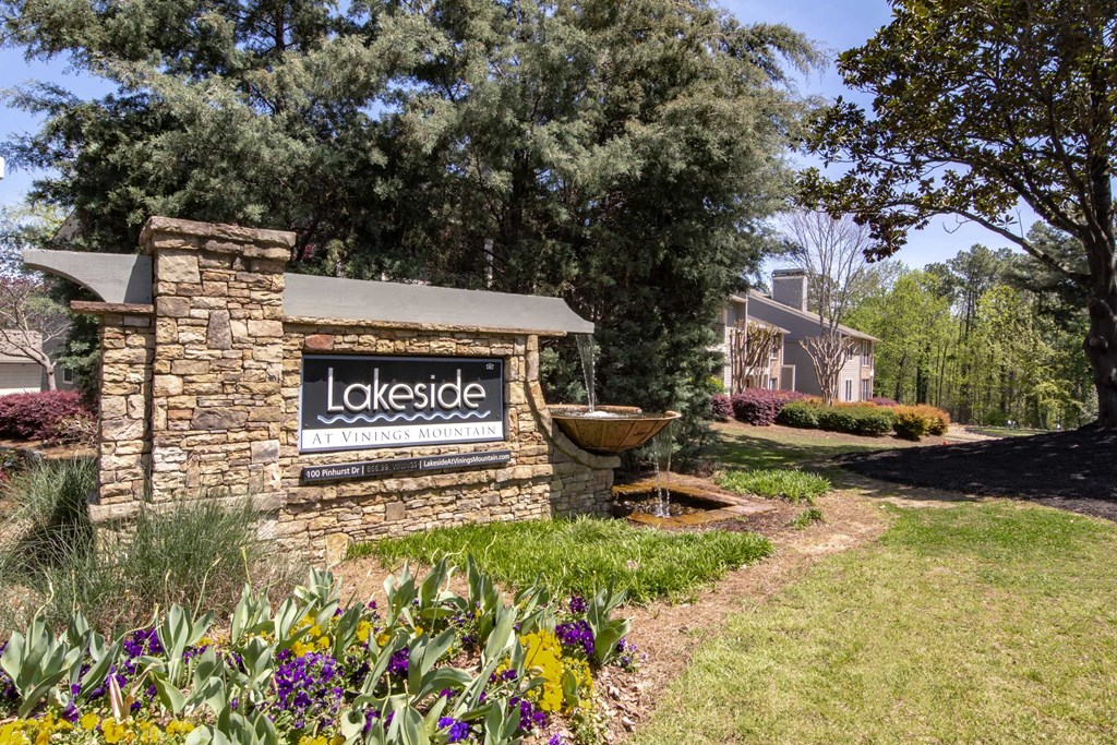 a stone building with a lakeside sign and a fountain in a garden