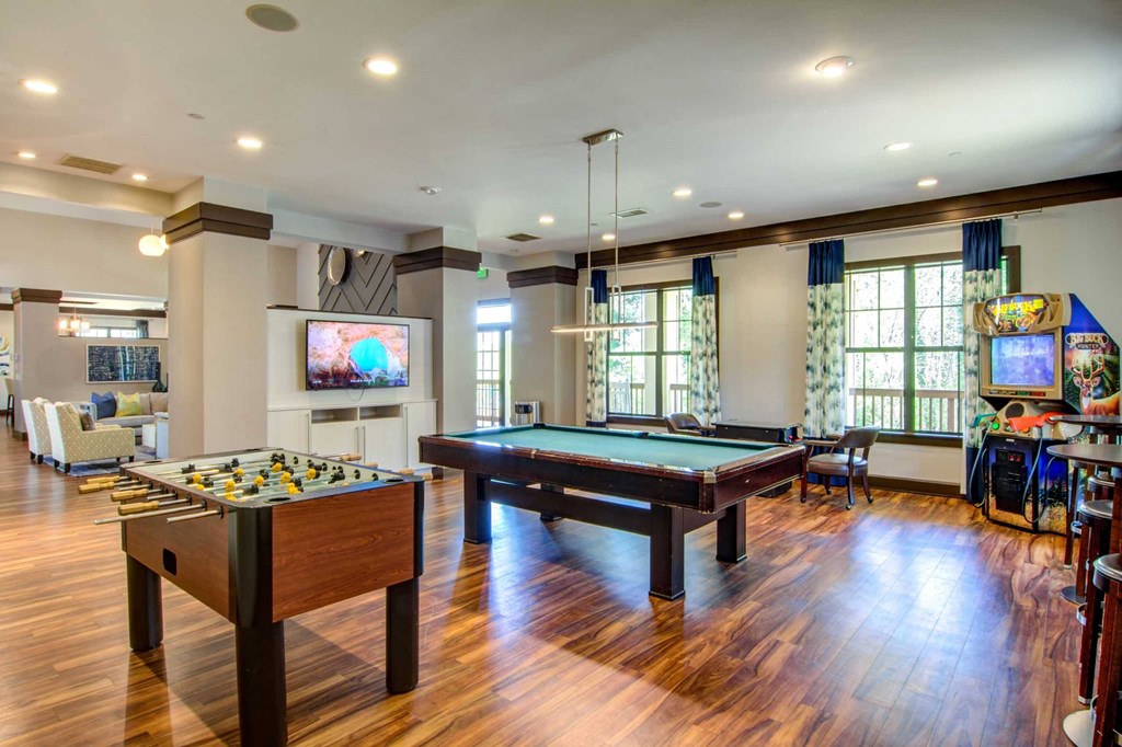 a game room with two pool tables and a tv