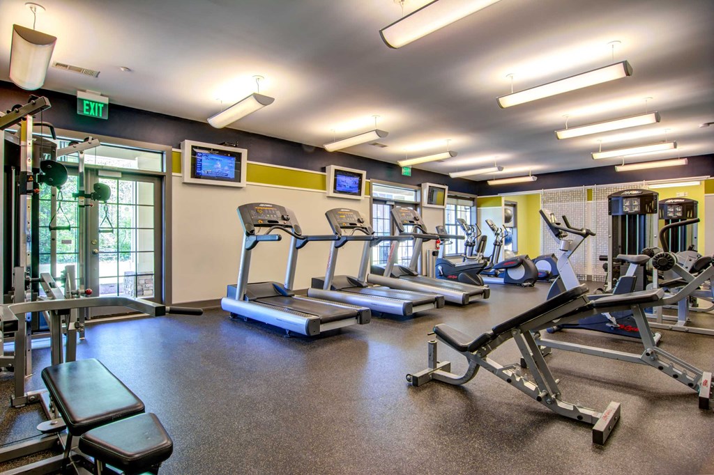 a gym with cardio equipment and weights on the floor
