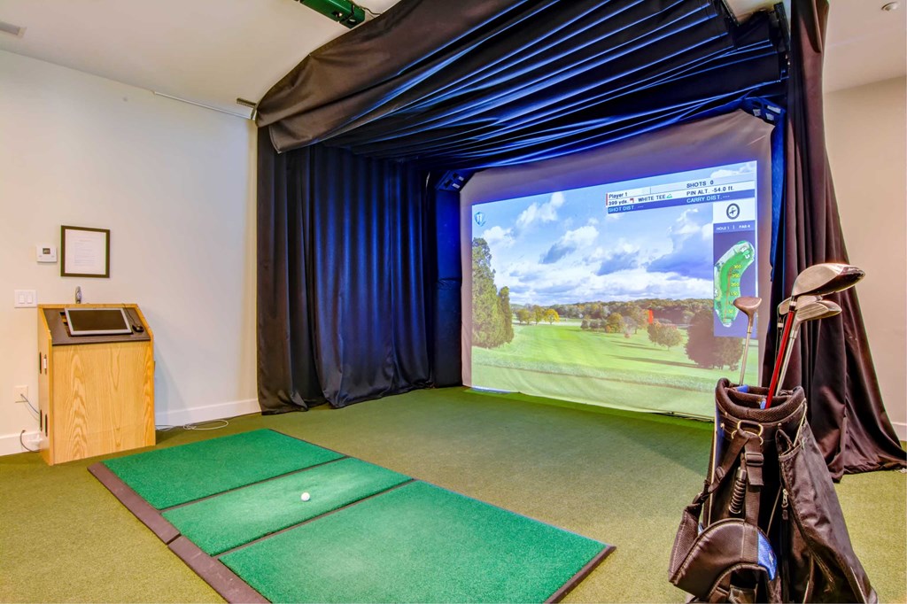 a room with a golf simulator and a video game on the wall