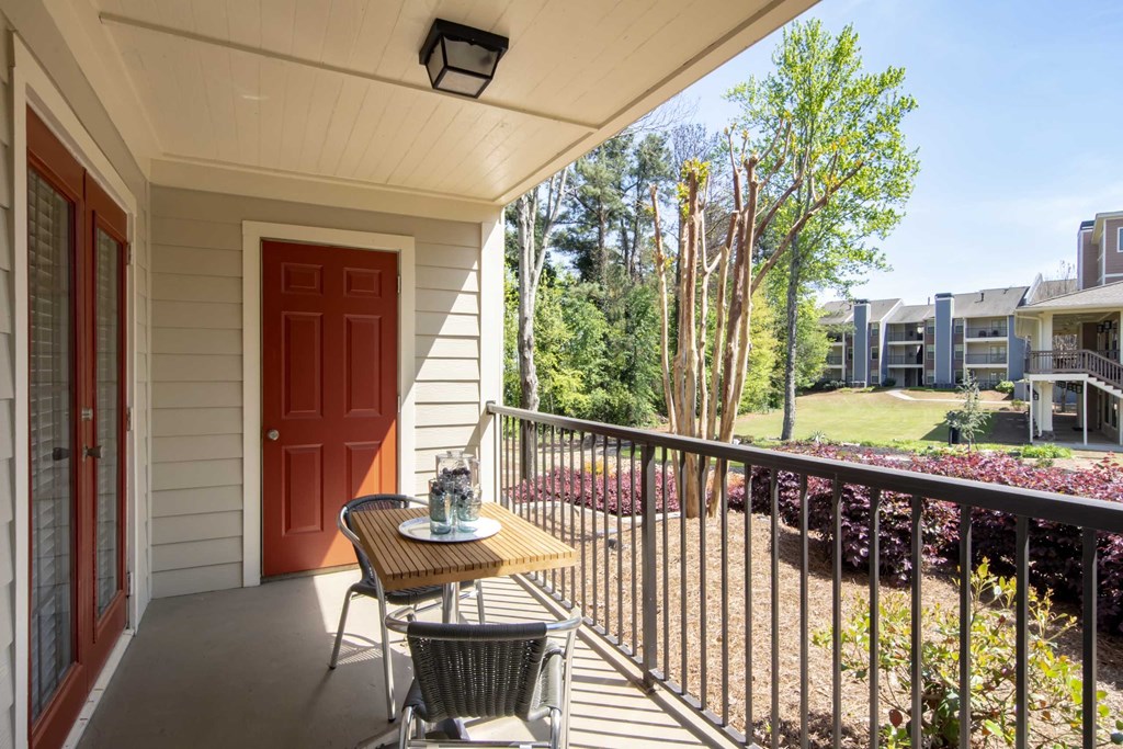 a balcony with a table and two chairs and a red door