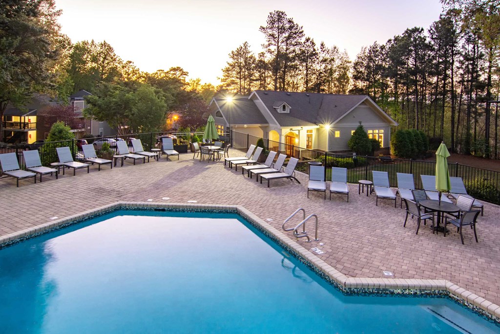 a swimming pool with chairs and a house in the background