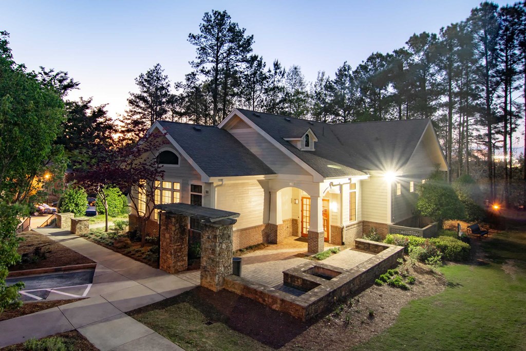 a house with lights on in a backyard with trees