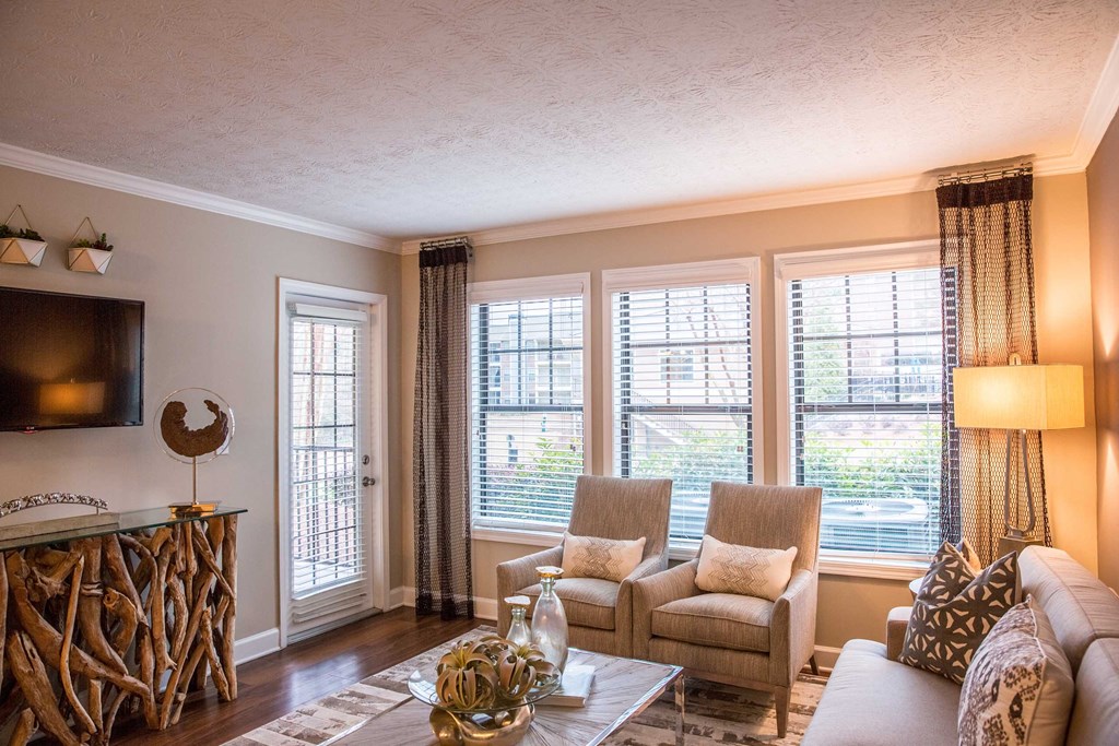 a living room with a couch and chairs and windows