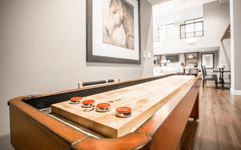 a shuffleboard table in a living room with a dining room in the background