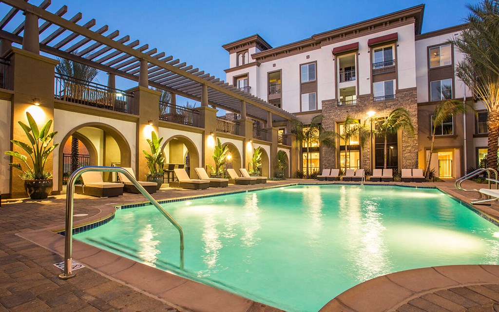 a swimming pool in front of a hotel at night