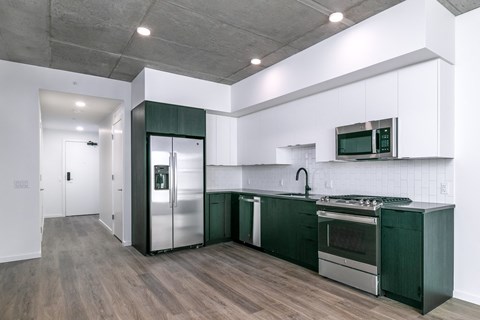 a kitchen with green cabinets and a stainless steel refrigerator