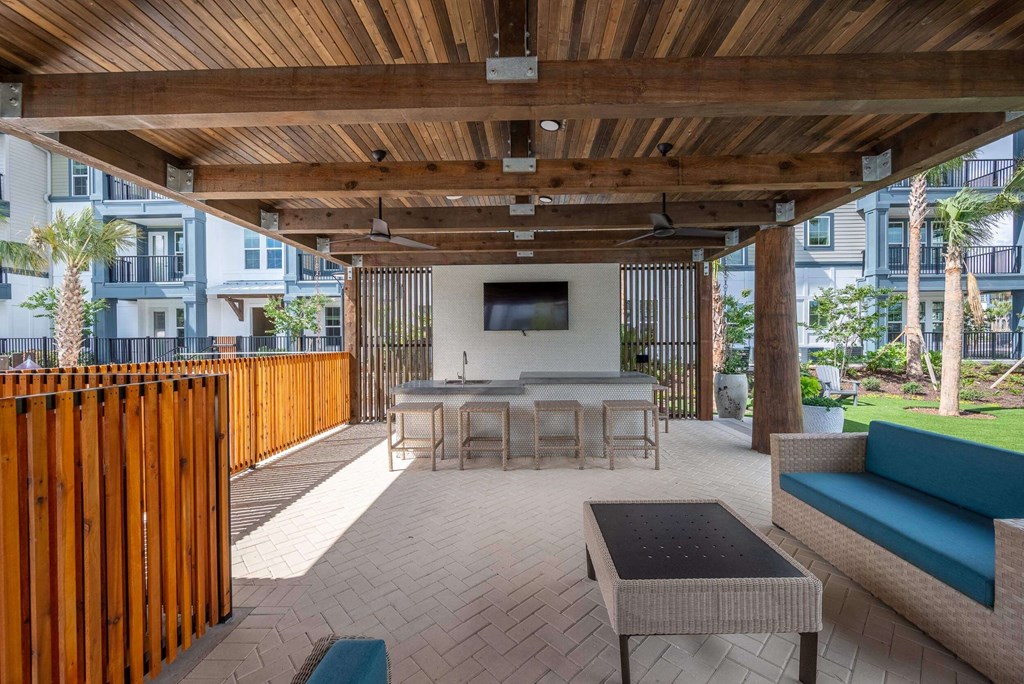 a patio with a table and chairs under a wooden roof